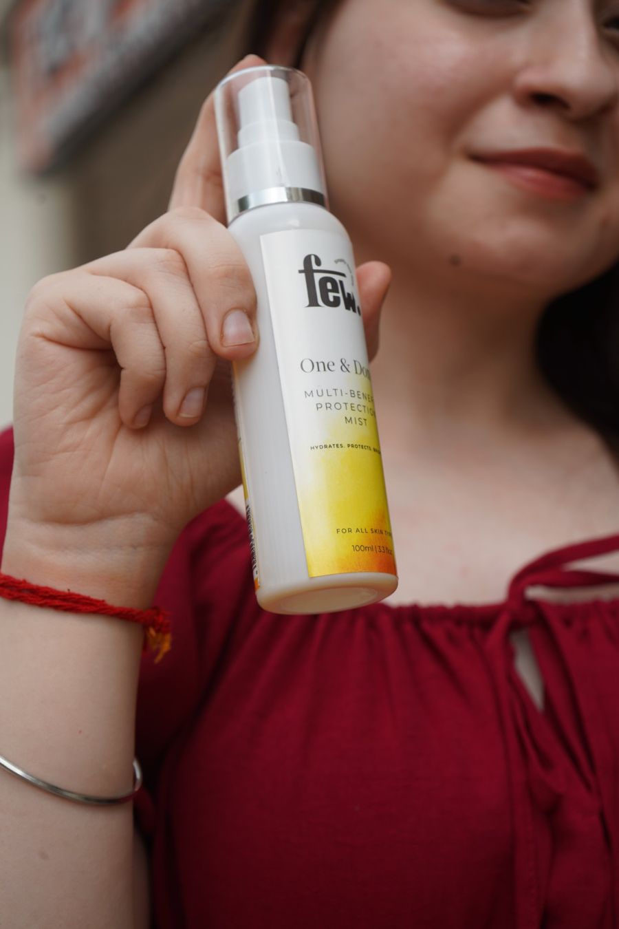 A woman holding FEW mist beside her face